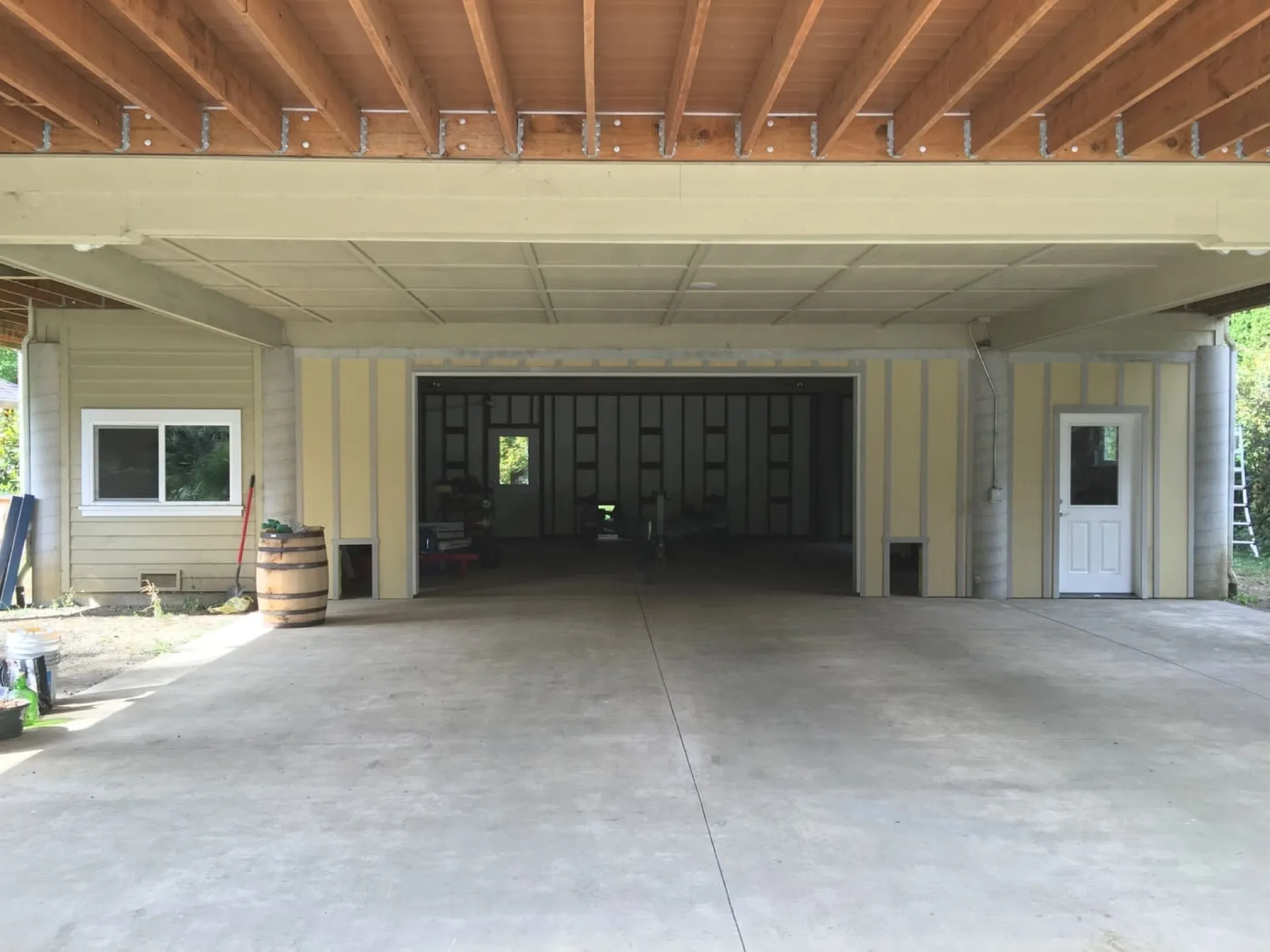 Empty two-car garage with poured concrete floor and open ceiling framing before a Boss PDX conversion