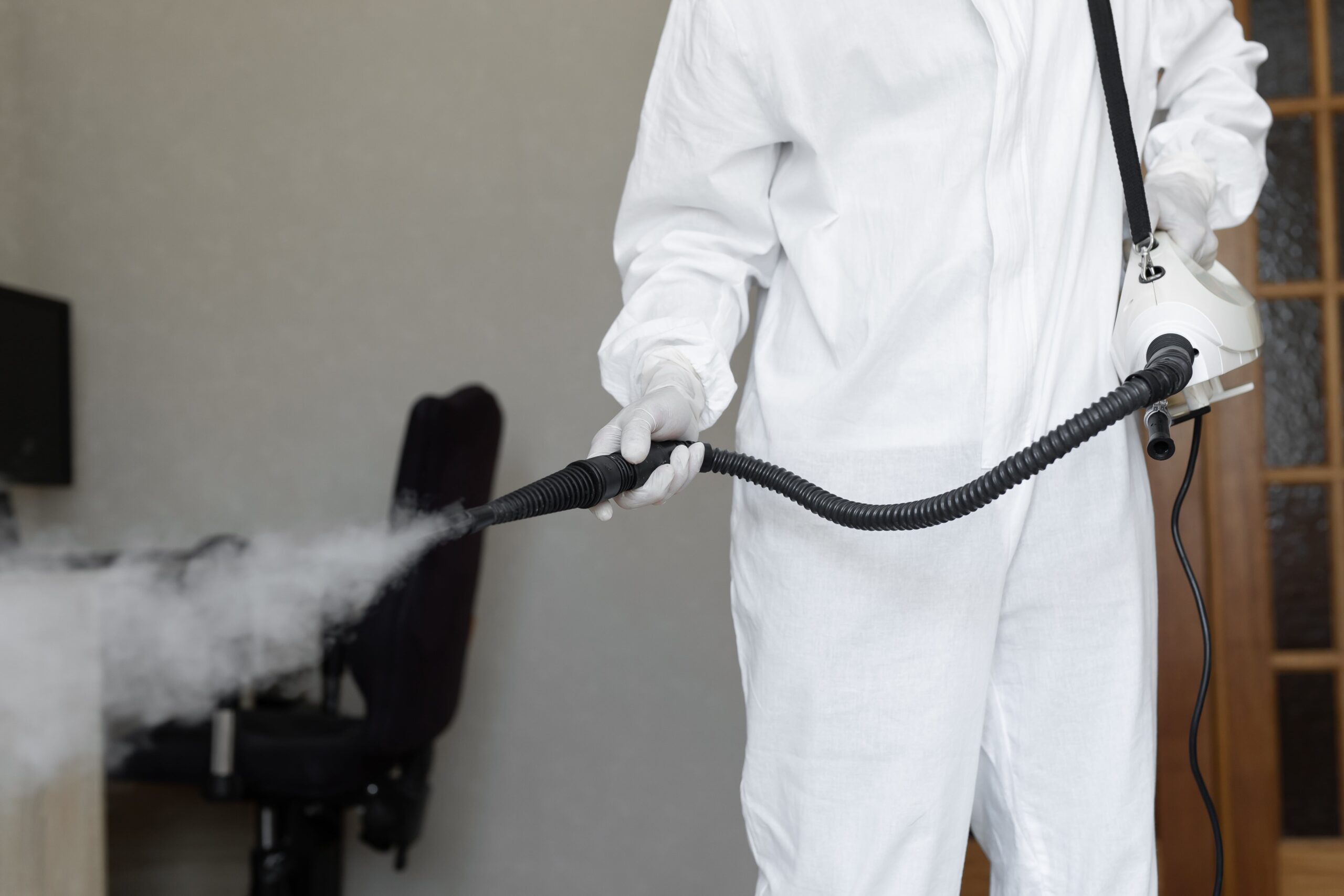 man getting rid of mold while wearing a hazmat suit